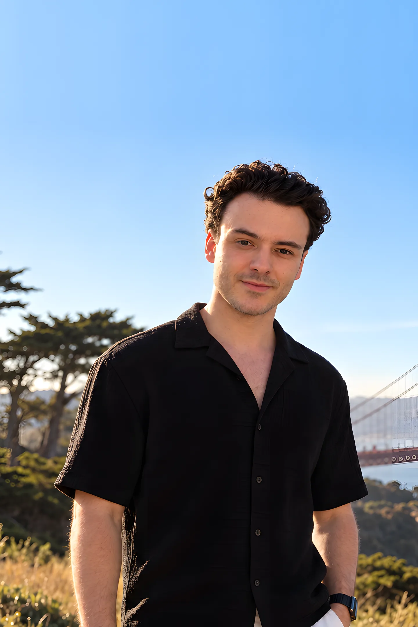 Misha Gavura smiling on a hillside in San Francisco, with the Golden Gate Bridge behind him.